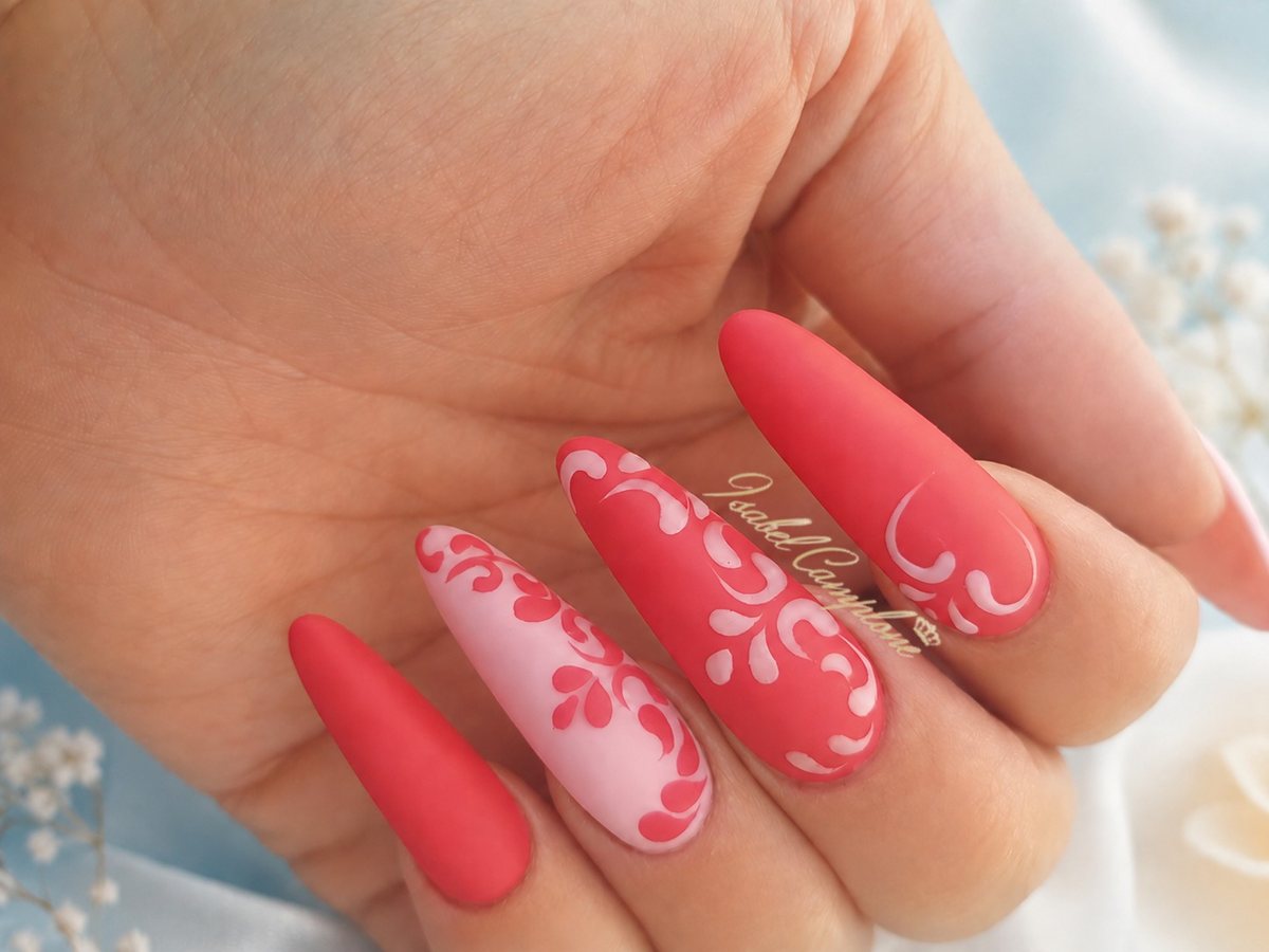 Main complète en nail art : motifs baroques blancs sur fond rouge mat, réalisation Isabel Camplone